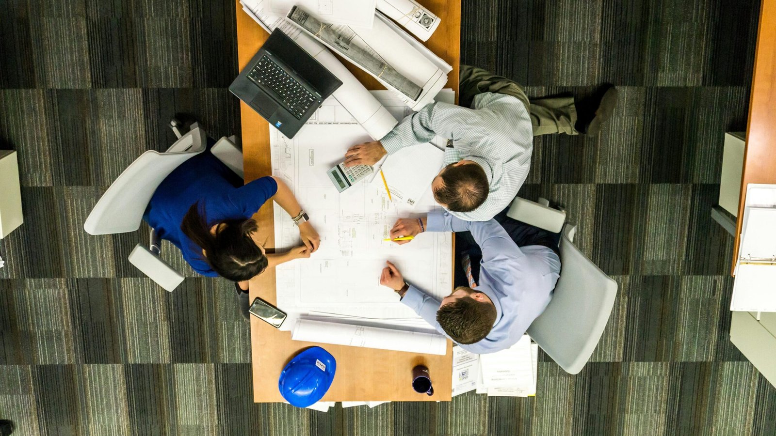 Top view of a team working on construction plans in an office setting.